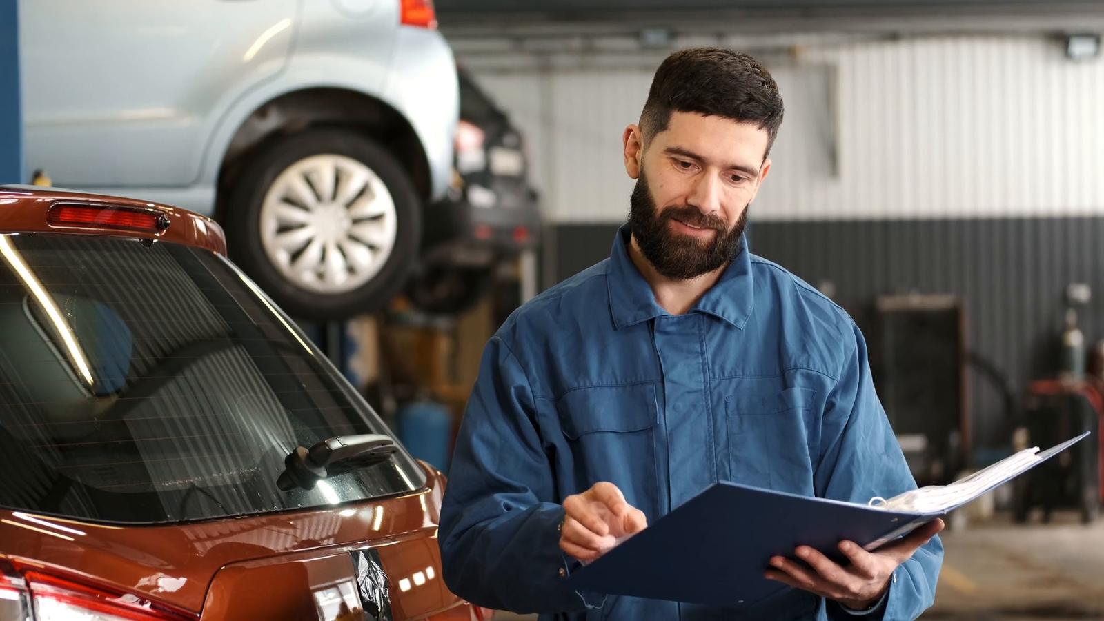 A manager in a workshop, reading through paperwork in a folder.